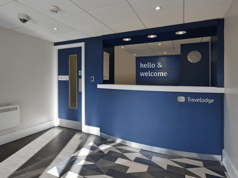 Travelodge hotel lobby with welcome desk and geometric floor.