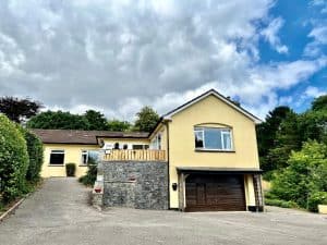 Yellow suburban house with driveway and cloudy sky.