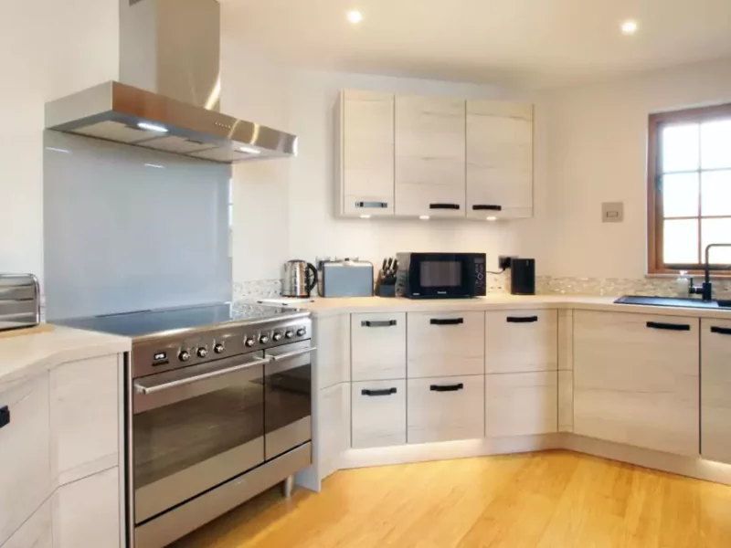 Modern kitchen with stainless steel appliances and wooden floor.