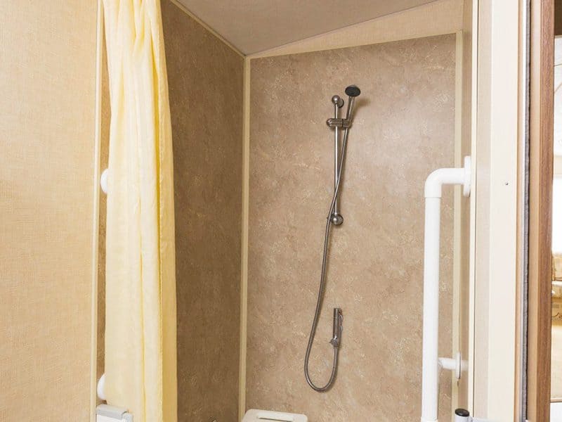 Modern RV shower with beige tiles and curtain.