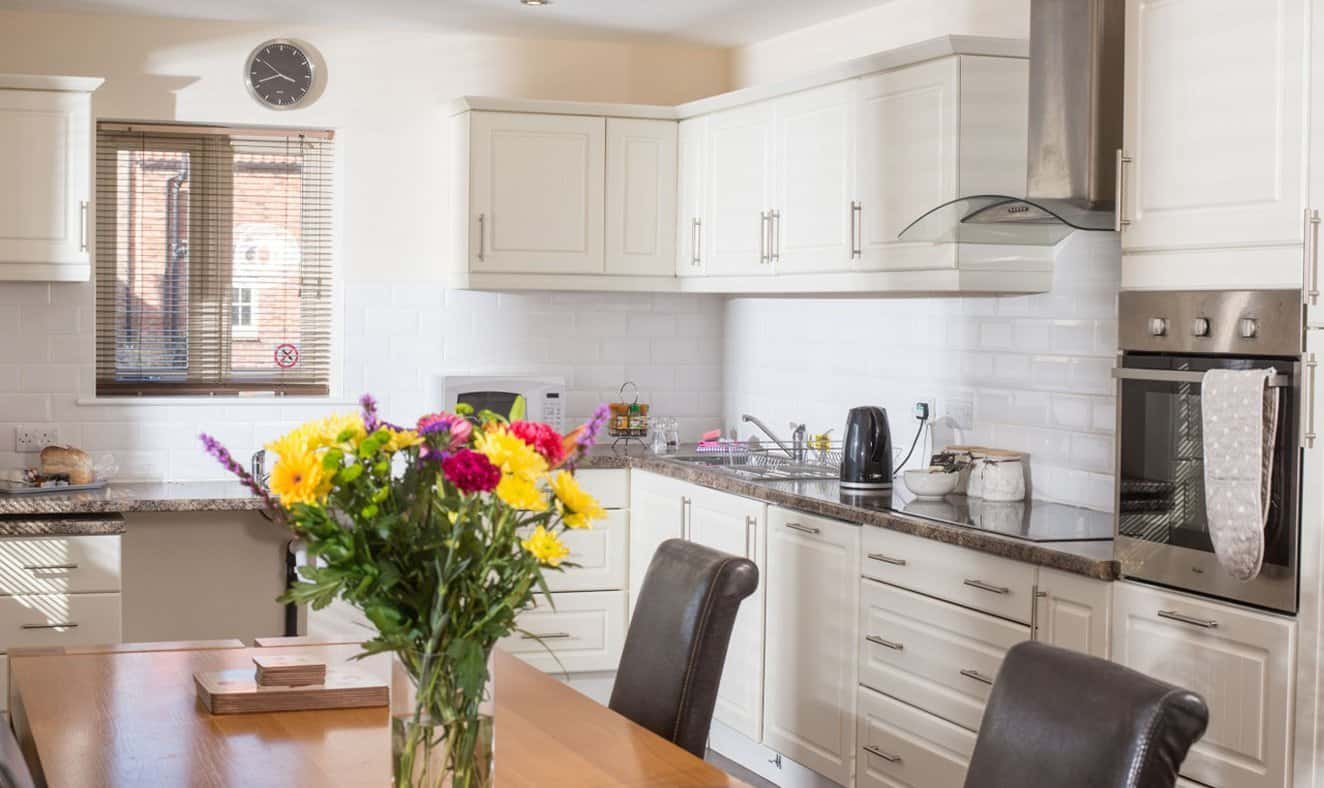 Bright, modern kitchen with flowers and white cabinets.
