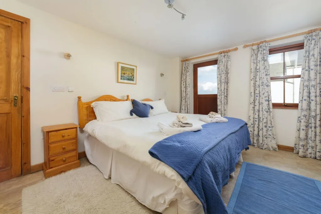 bedroom with wooden double bed, white bedding and blue throw