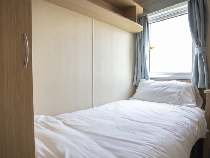 Compact modern bedroom with clean white bedding and window.