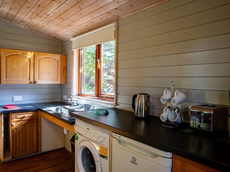 Cozy wooden cabin kitchen with modern appliances and window view.