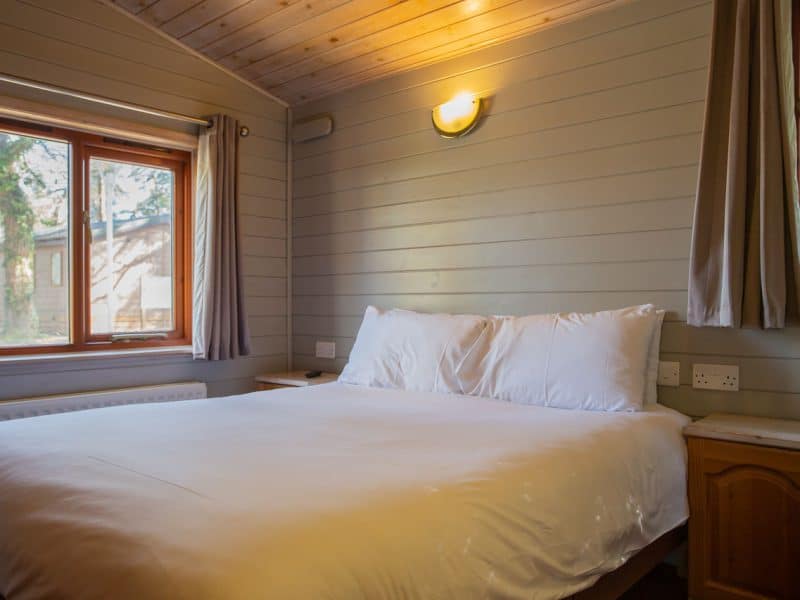 Cozy wooden cabin bedroom with large bed and windows.