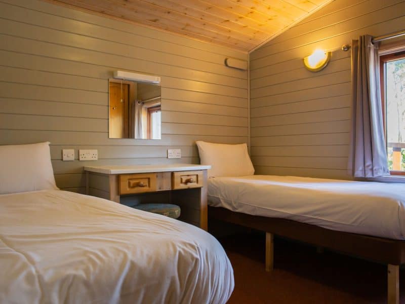 Cozy twin bedroom with wooden interior and natural light.