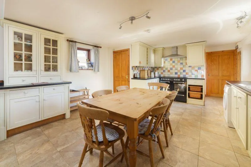 Farmhouse Kitchen with white cabinets and wooden dining table.