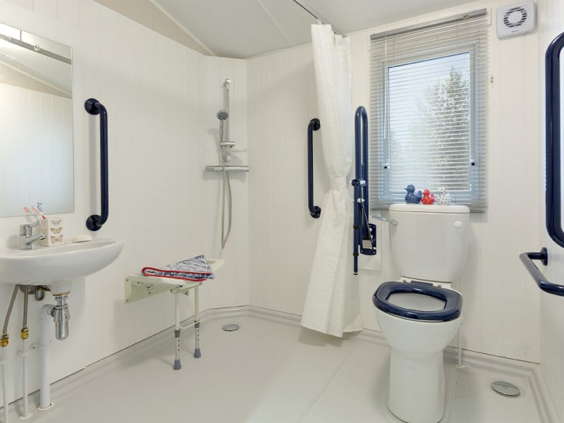 Accessible bathroom with support bars and adapted fixtures.