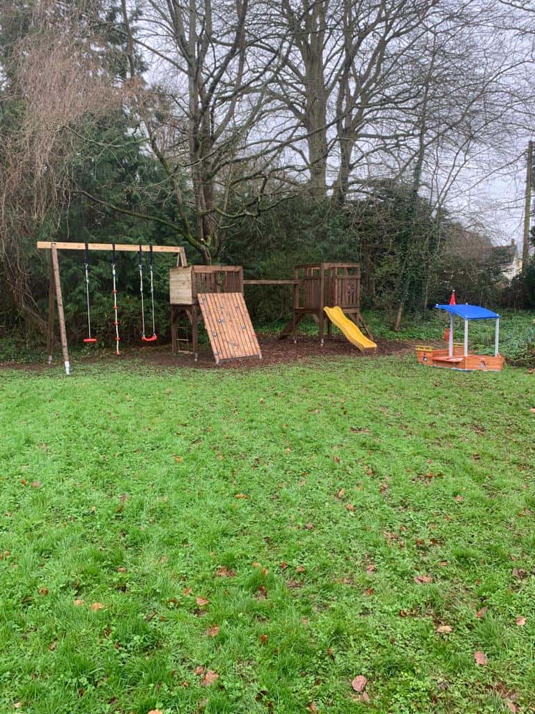 Outdoor playground with swings, slide, and climbing wall