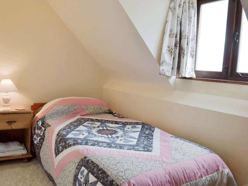 Cozy attic bedroom with quilted bed and window