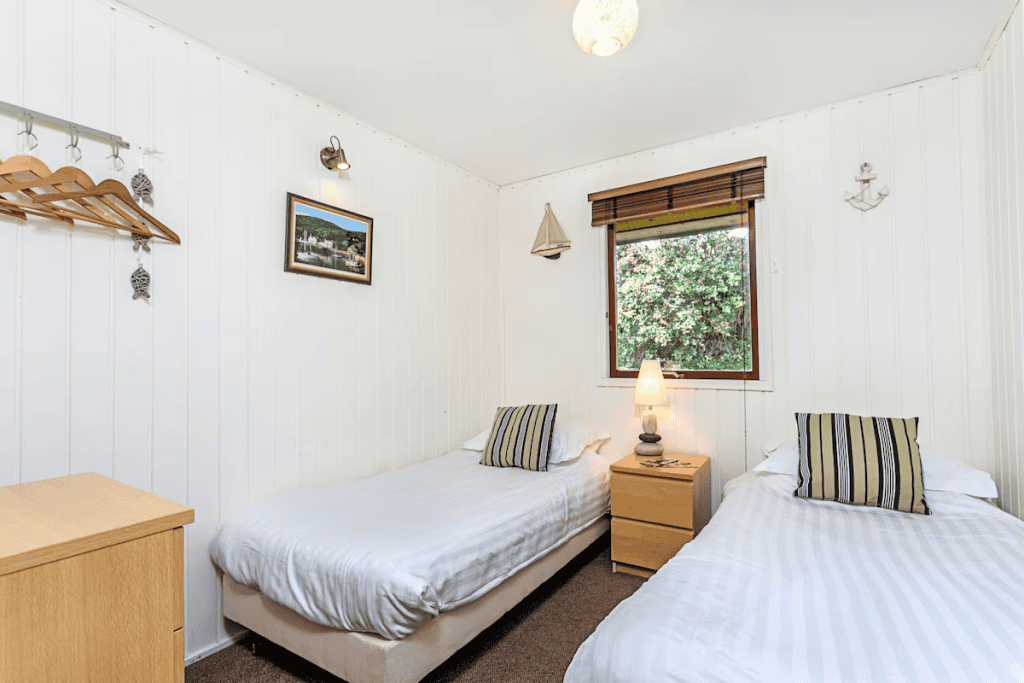 Bright twin bedroom with nautical decor and garden view