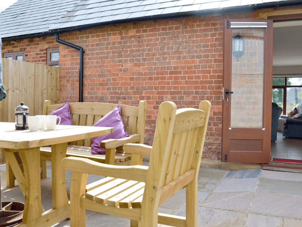 Cozy outdoor patio with wooden furniture and brick wall