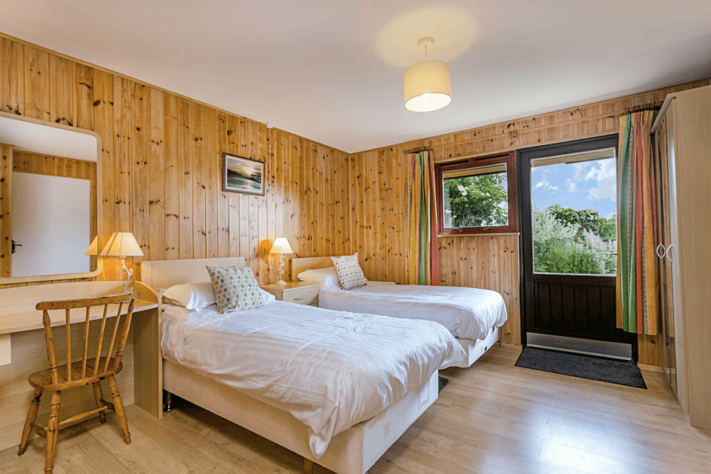 Bright wooden cabin room with two beds and garden view