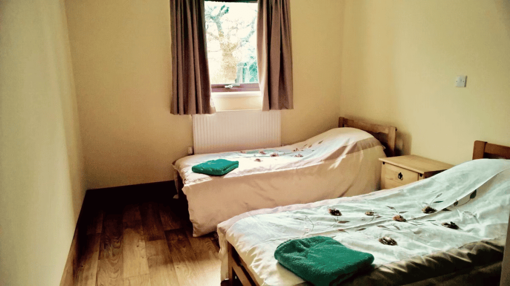 Bright twin bedroom with hardwood flooring and window view