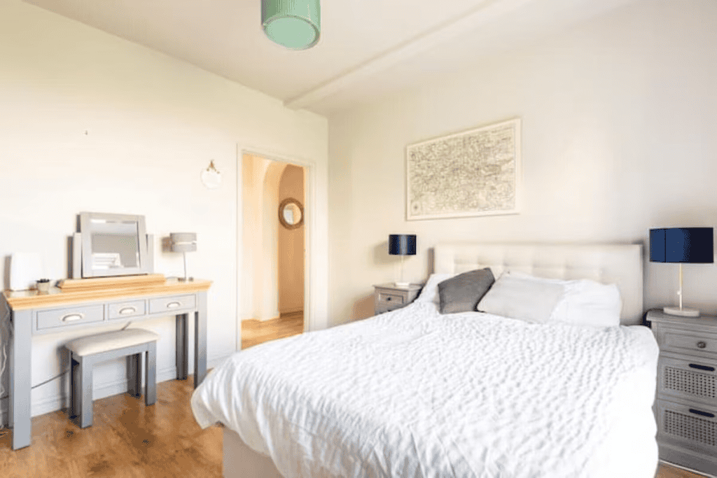 Bright minimalist bedroom with white bed and wooden furniture