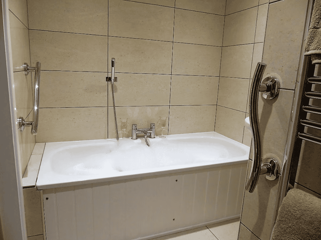 Modern bathroom with filled bathtub and wall tiles