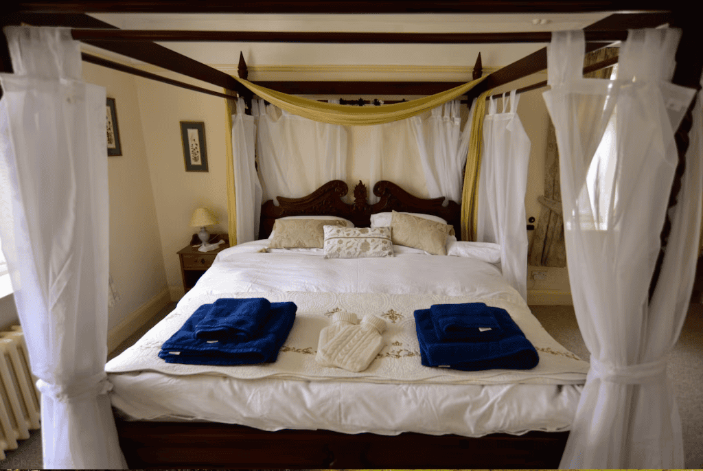 Elegant canopy bed with white drapes and blue towels