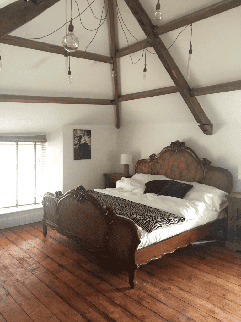 Cozy bedroom with ornate wooden bed and exposed beams