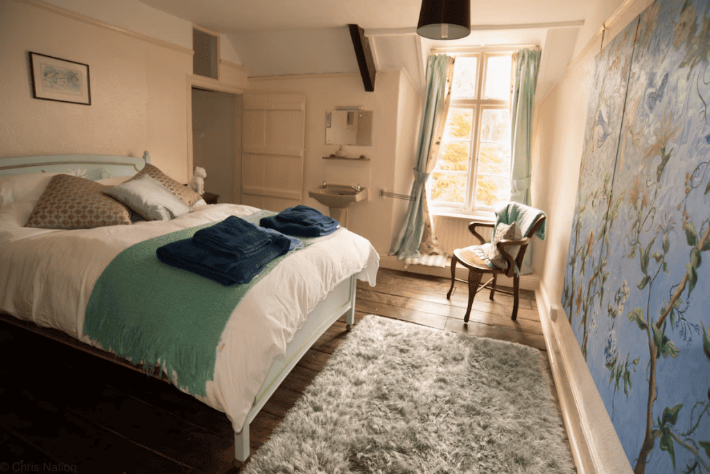 Cozy bedroom with floral mural and wooden floor