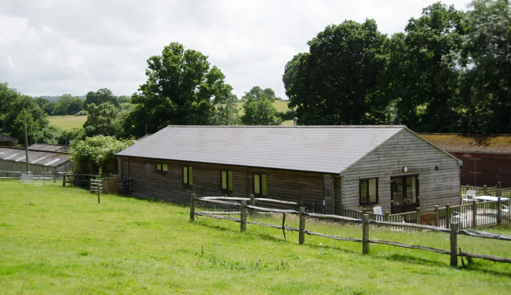 Wooden barn in green pasture with surrounding trees