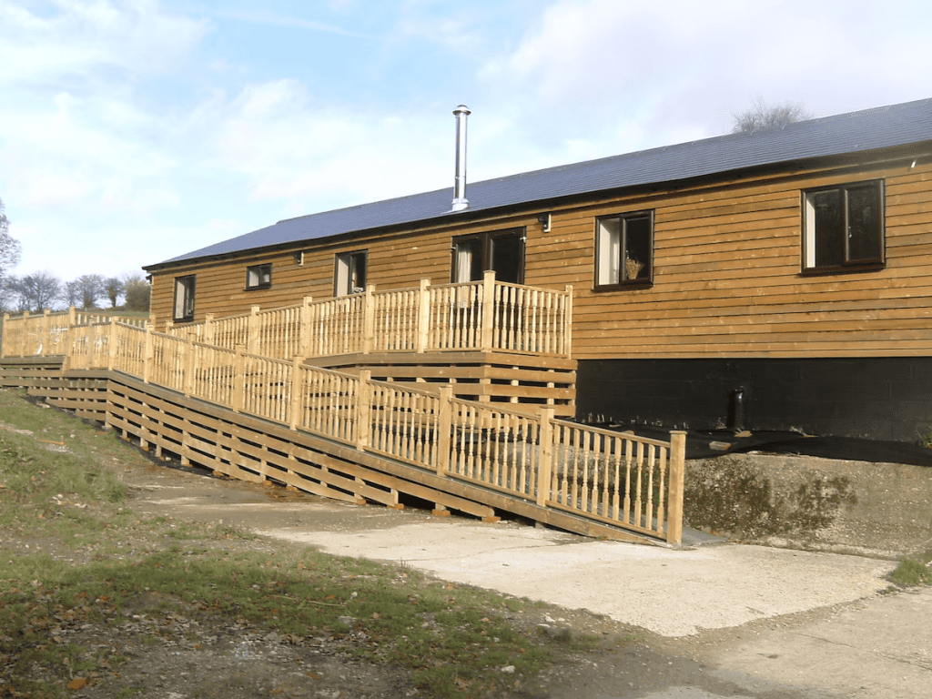 Wooden cabin exterior with deck and railing under sunny sky