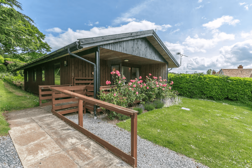 Wooden cabin with rose bushes and lush green lawn