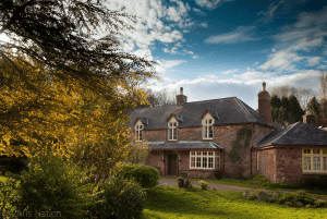 Historic red brick house surrounded by autumn foliage