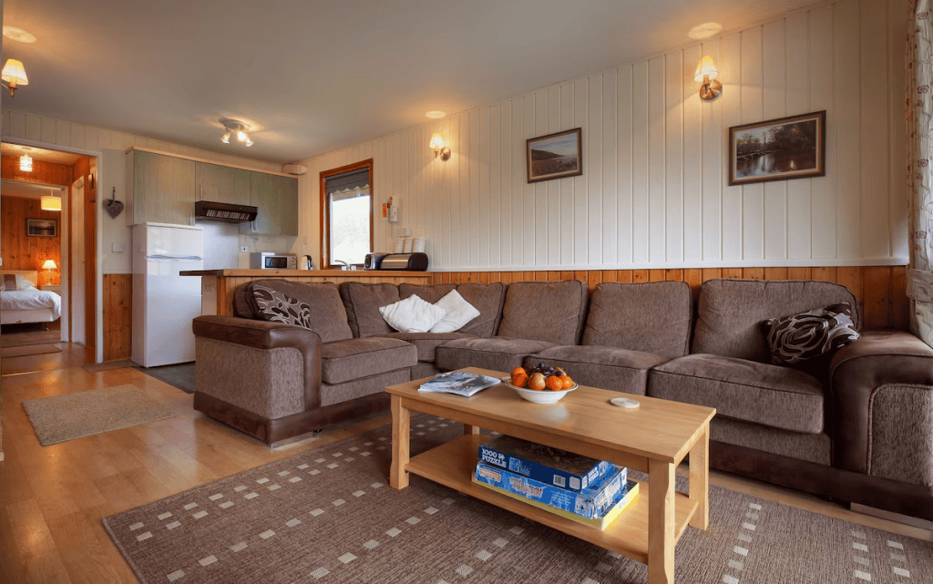 Cozy cabin living room with kitchenette and plush sofas.