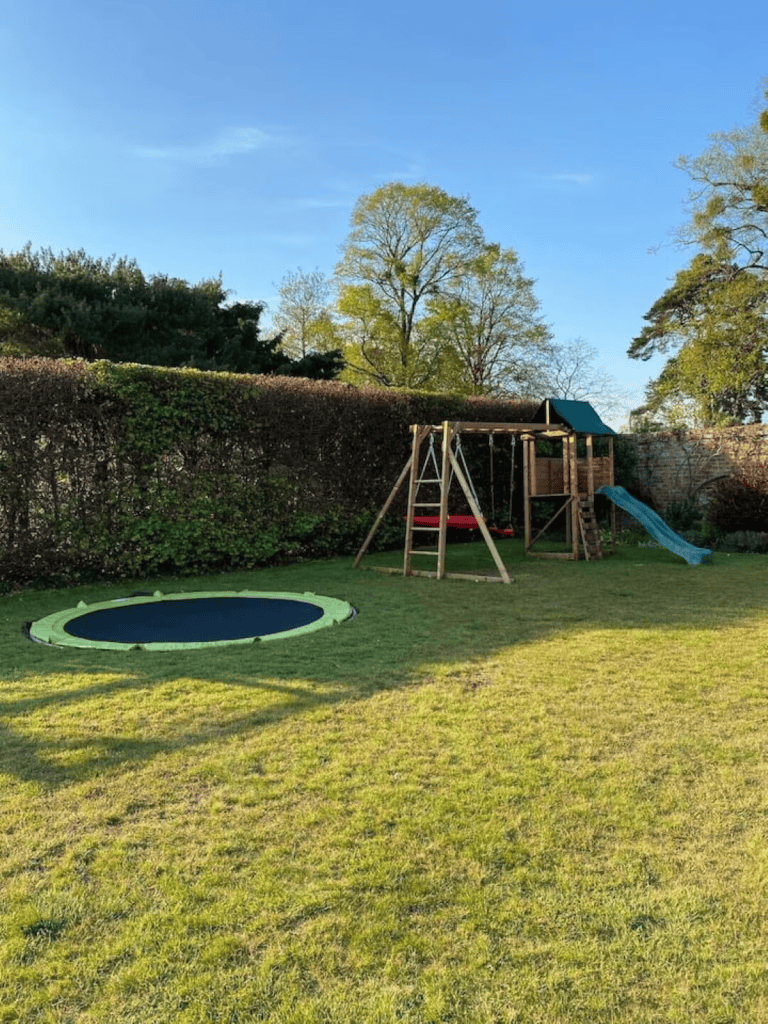 Sunny backyard with playground and in-ground trampoline