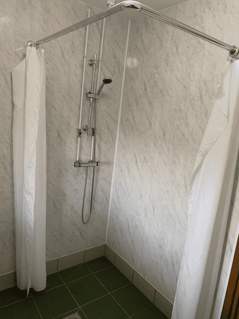 Corner shower stall with curtain and wall-mounted fixtures