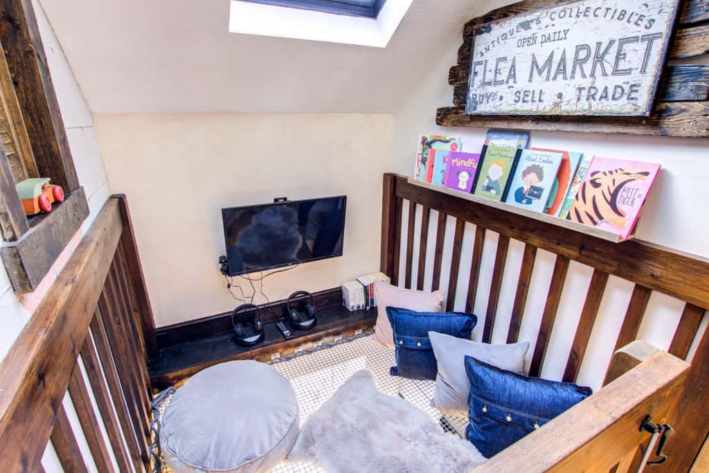 Cozy attic reading nook with cushions and TV