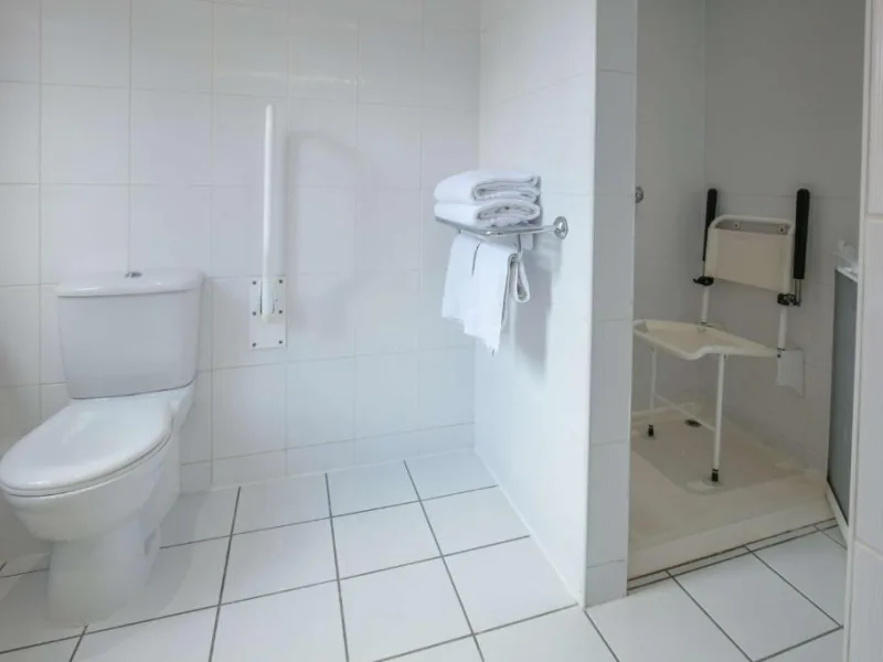 Accessible bathroom with white tiles and safety handles