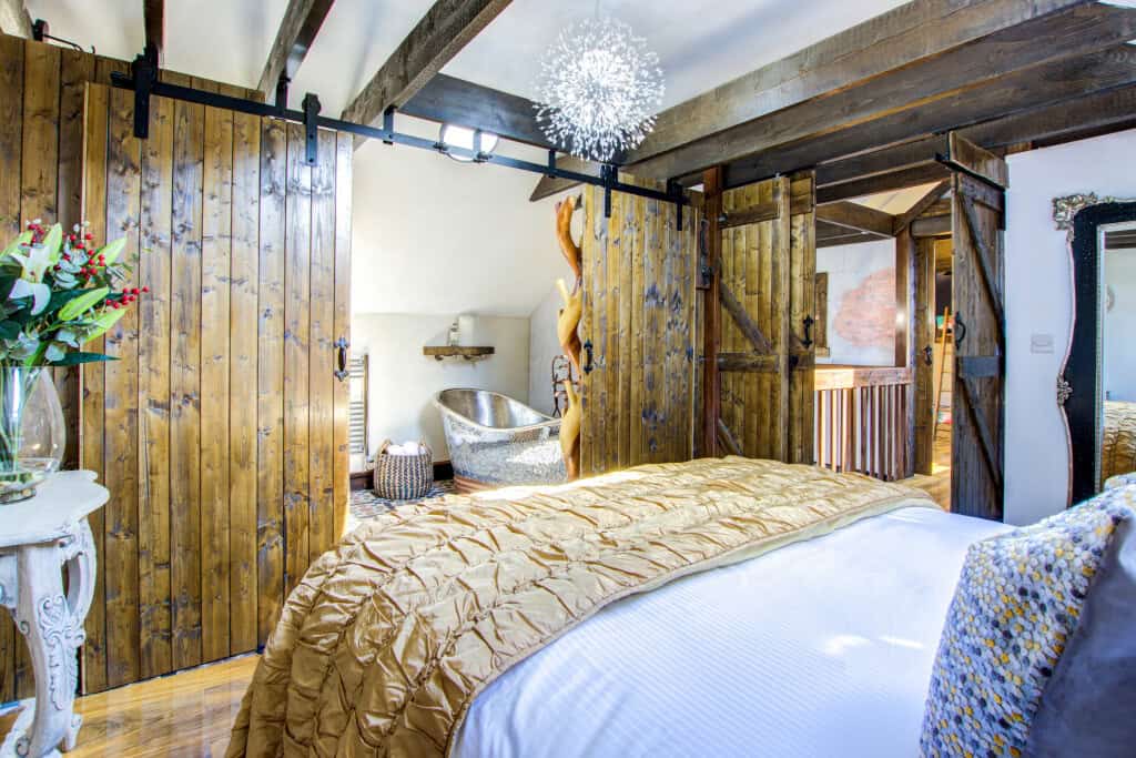 Rustic bedroom with wooden sliding doors and metallic tub