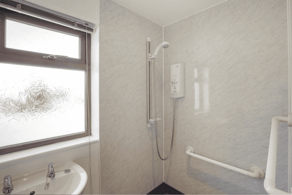 Accessible bathroom with shower, handrails, and frosted window