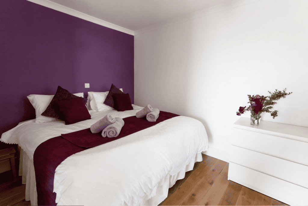 Elegant bedroom with purple accent wall and white furniture