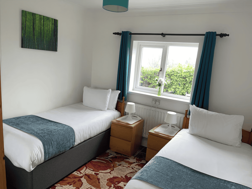 Bright twin bedroom with teal accents and garden view