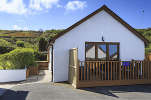 White cottage with deck and surrounding greenery