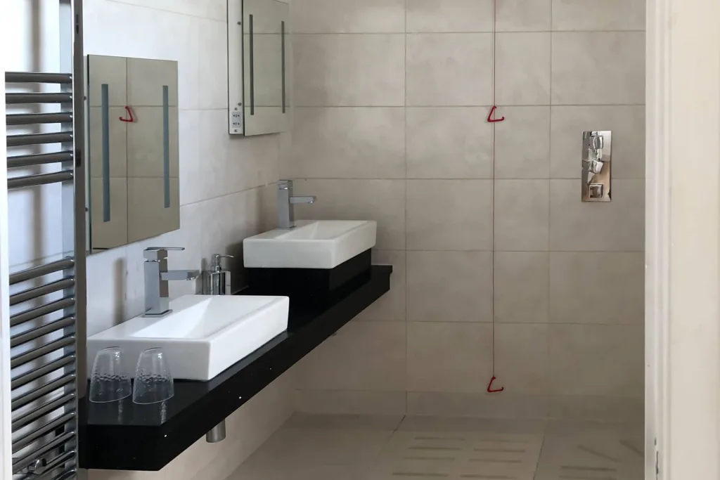 Modern bathroom with twin sinks and tiled walls.