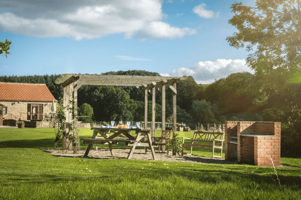 Sunny garden with picnic table, pergola, and brick barbecue