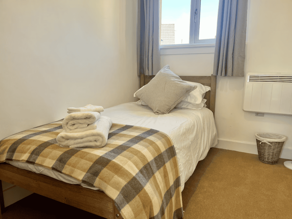 Cozy bedroom with plaid blanket and white towels