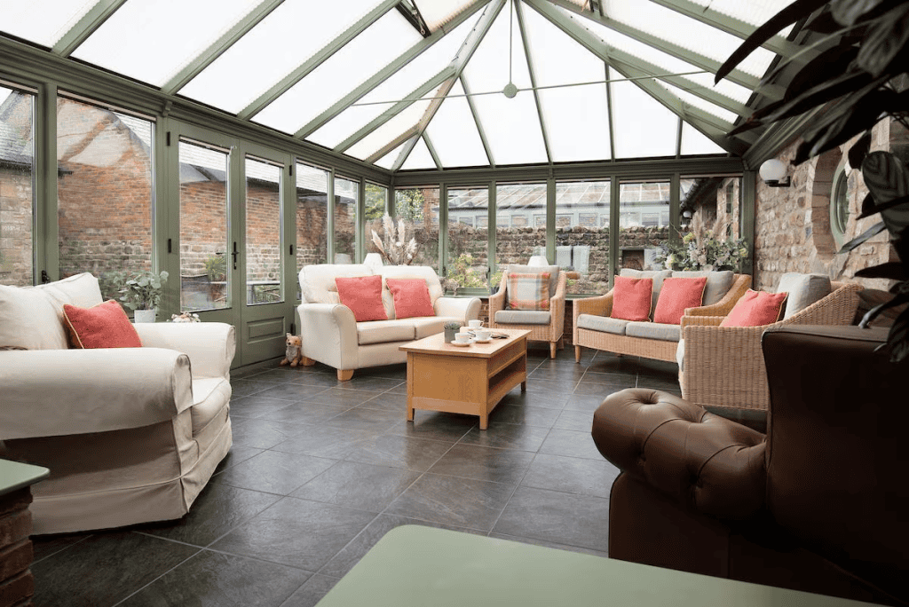 Bright sunroom with comfortable sofas and glass roof.