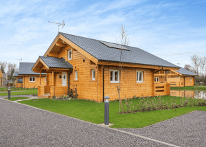 Modern wooden cabin with landscaped garden and driveway