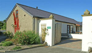 Sunny rural guesthouse with lush garden and open gate