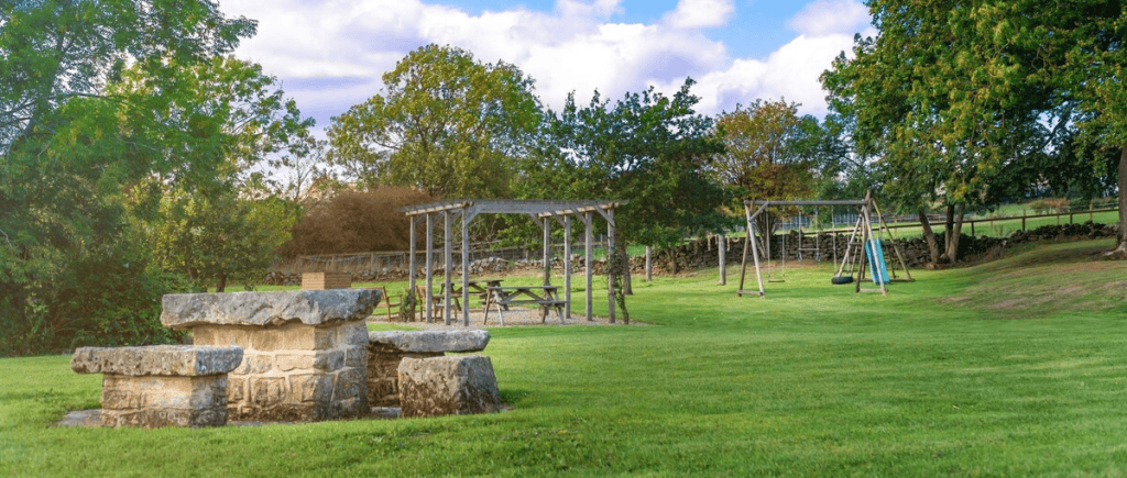 Scenic park with stone BBQ, swings, and green grass