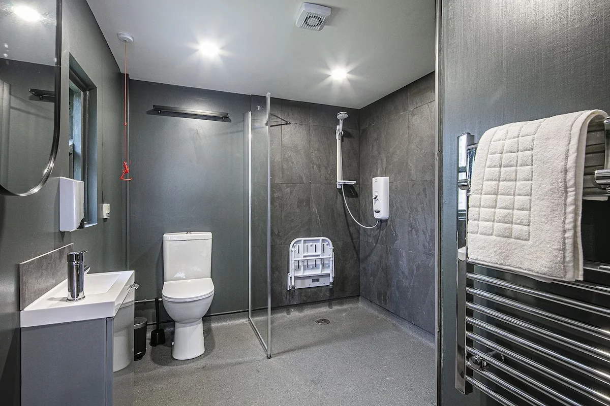 Fully accessible wet room with step free shower, wall mounted shower seat and emergency pull cord alarm