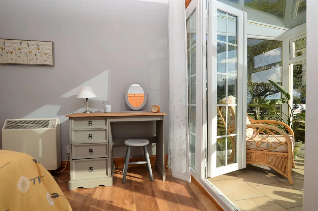 Bright sunroom with desk, plants, and open French doors