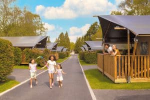 Families enjoying sunny day at holiday park with cabins