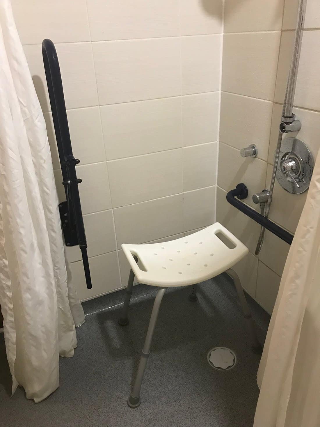Accessible shower stall with seat and handrails