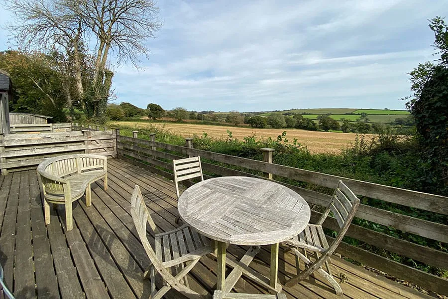 Rustic deck with table and chairs overlooking green field