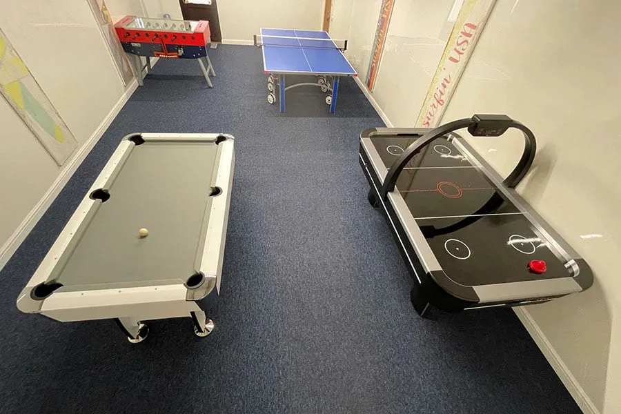 Indoor games area with pool, air hockey, and foosball tables